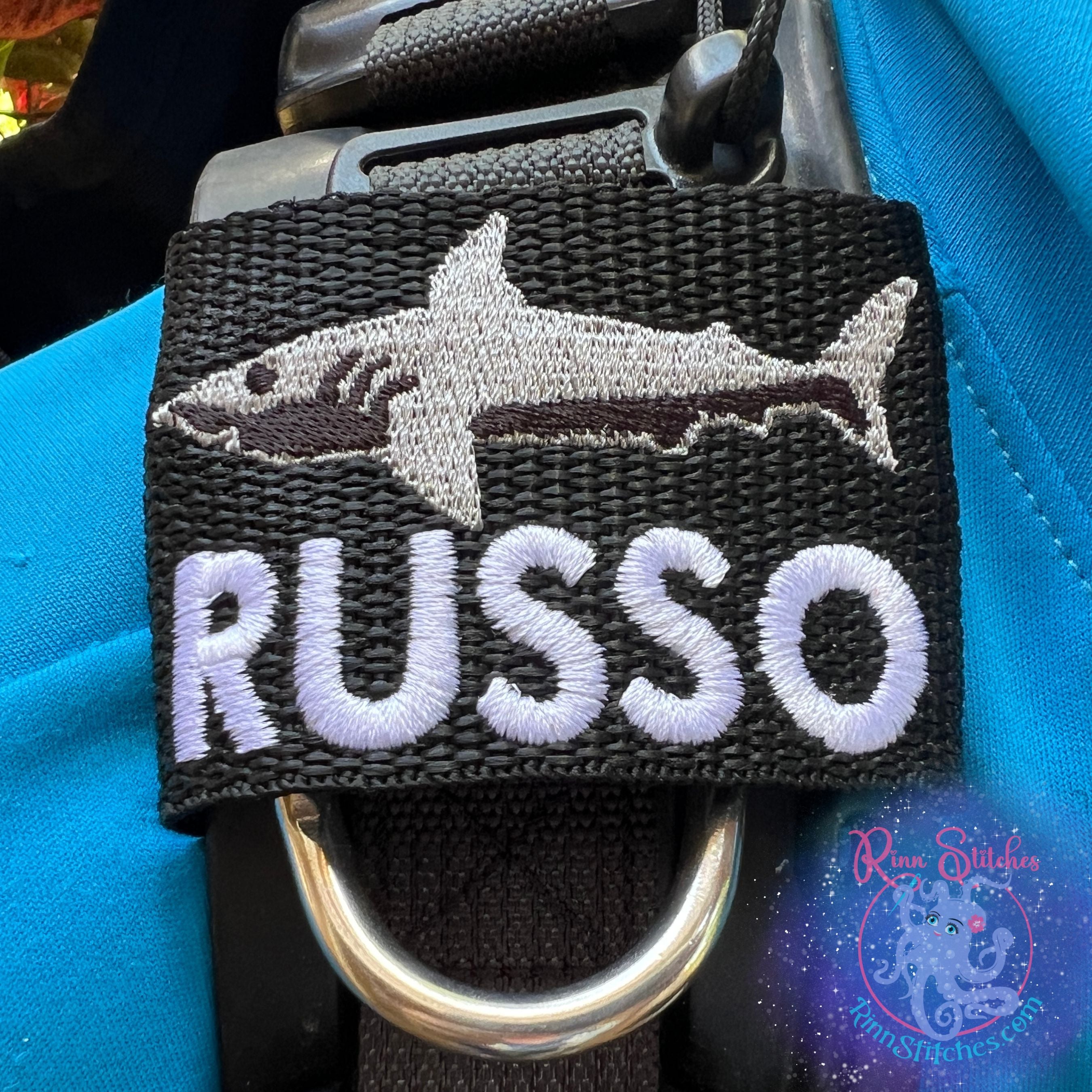 Shark personalized BCD tag silhouette design shark fin black thread colors custom embroidered name below scuba diving accessories By Rinn Stitches on Maui, Hawaii - Small Jacket Size - Scuba Pro Hydros, Zeagle Zena Name Russo in Deep Sea Diving Font in White Thread