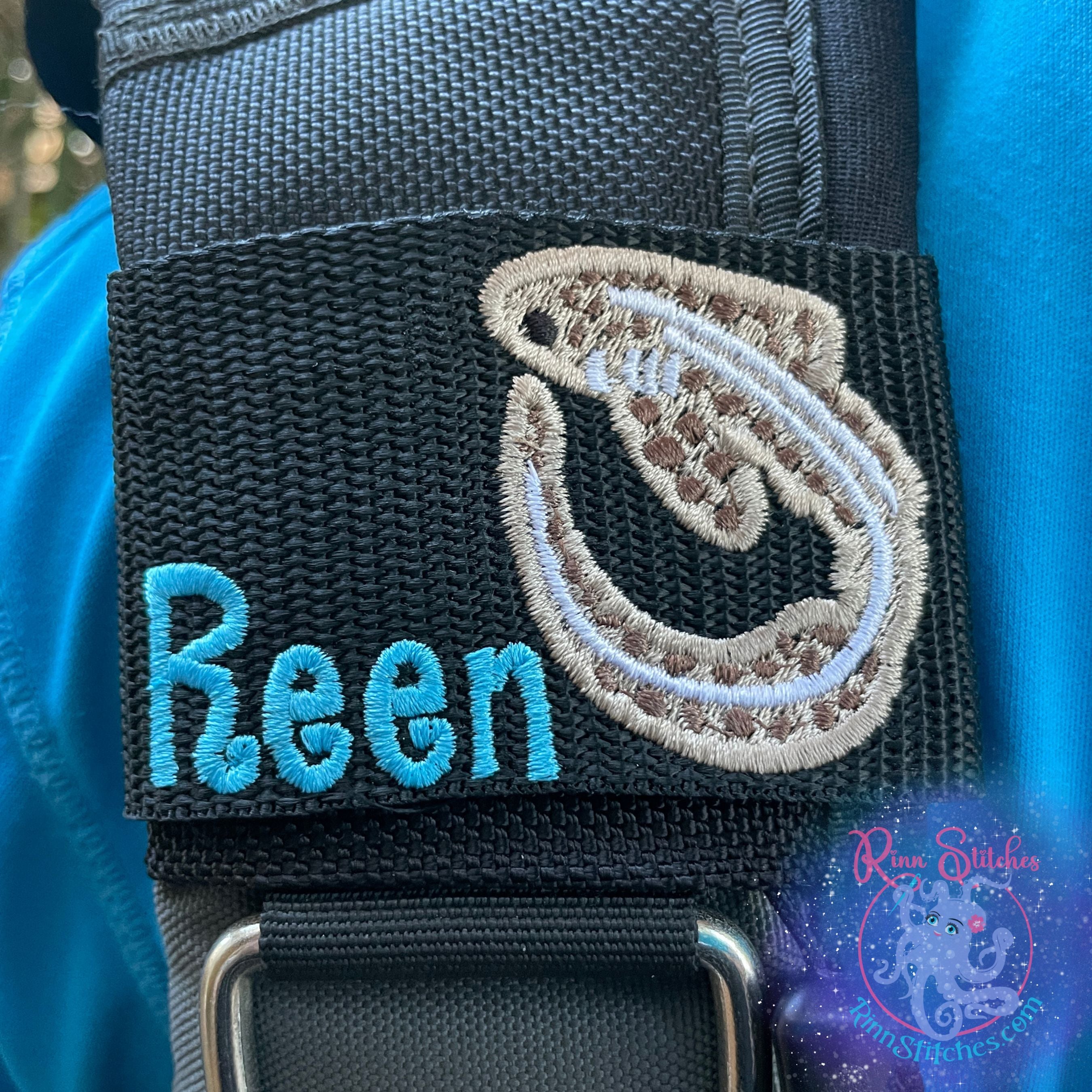 Personalized Zebra Shark BCD tag with sandy brown embroidered zebra shark design on right side and "Rachel" embroidered in white thread using Aloha Beaches font positioned at bottom left on black polypropylene webbing