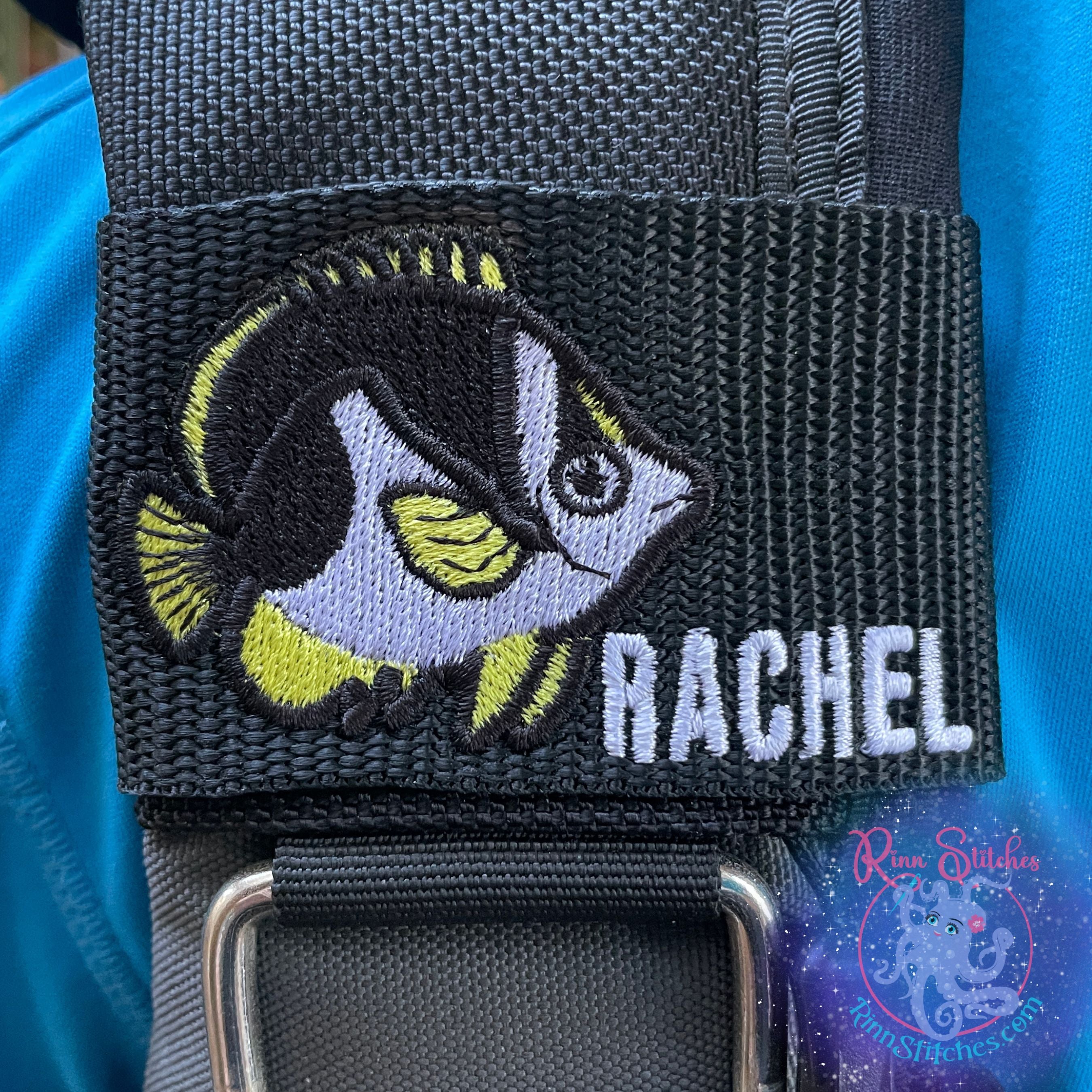 Personalized Tinkers Butterfly Fish BCD tag with yellow, black and white embroidered fish design and "Rachel" embroidered in white thread using Aloha Beaches font on black polypropylene webbing made in Maui, HI by Rinn Stitches