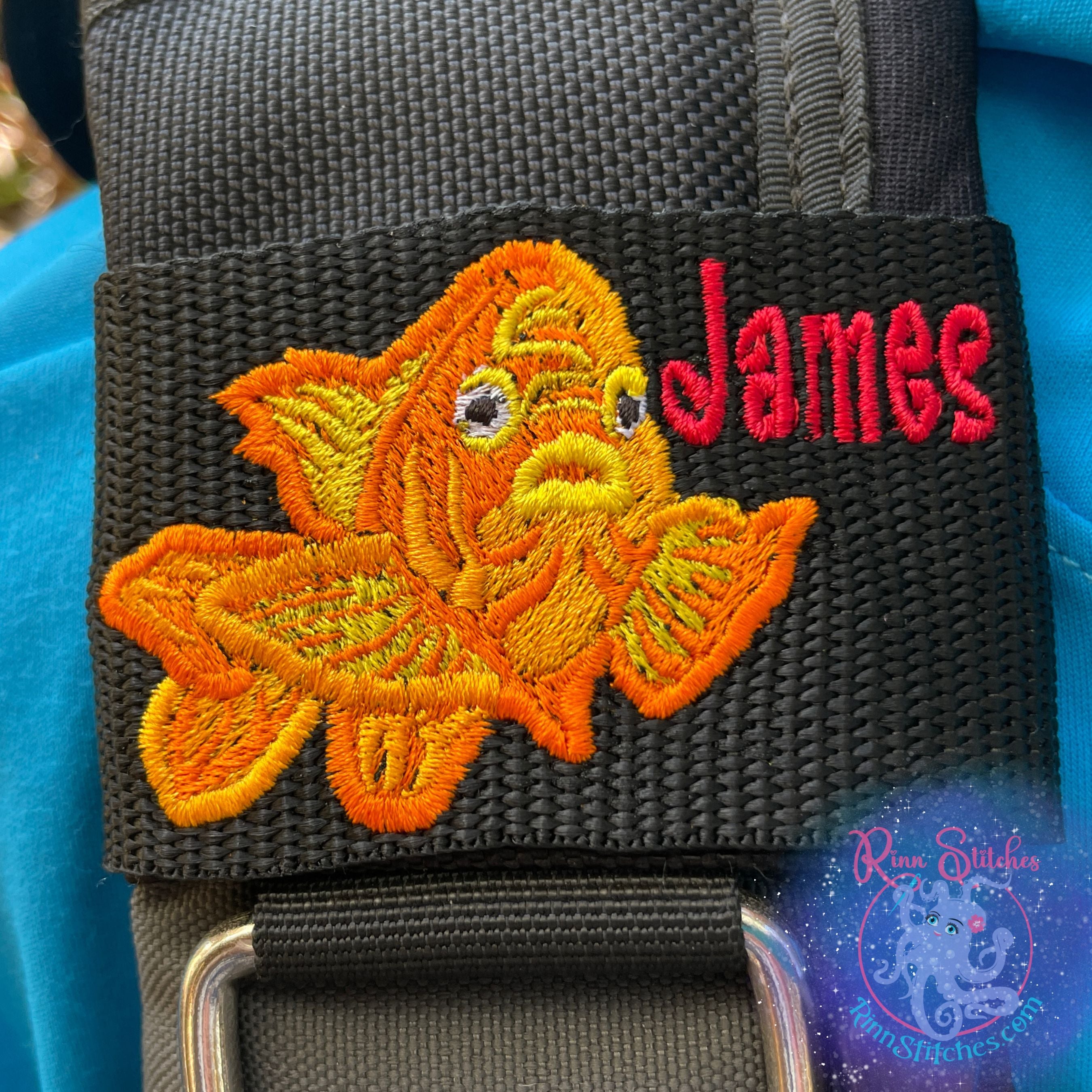 Garibaldi personalized BCD tag with "James" embroidered in red Tsunami font, featuring brilliant orange California state marine fish design on black polypropylene webbing with heavy-duty Velcro closure by Rinn Stitches on Maui, Hawaii