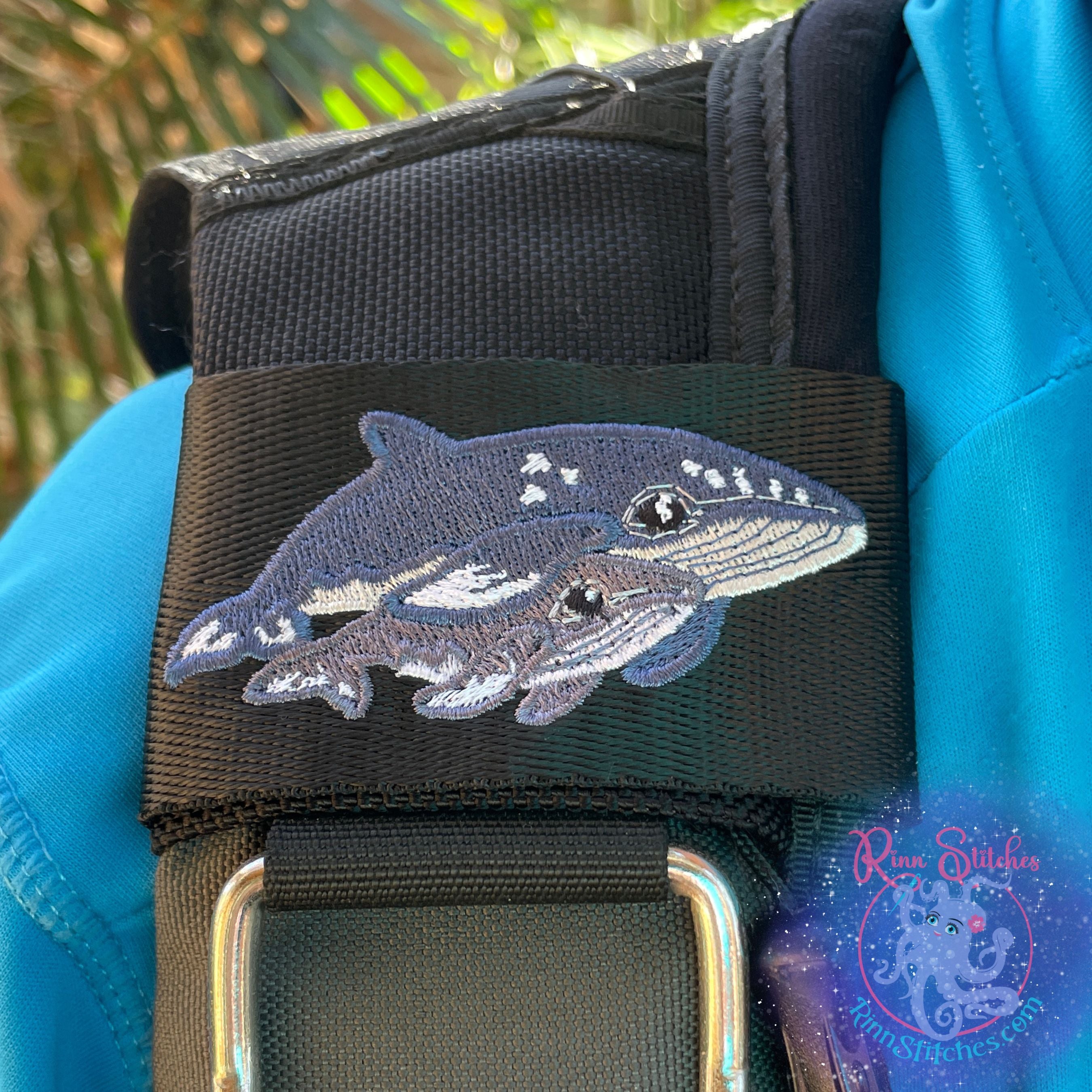 Embroidered BCD Tag with Mama and Baby Humpback whales on Black Polypropylene webbing attached to a Scuba Diving BCD. Designed and manufactured by Rinn Stitches on Maui, Hawaii