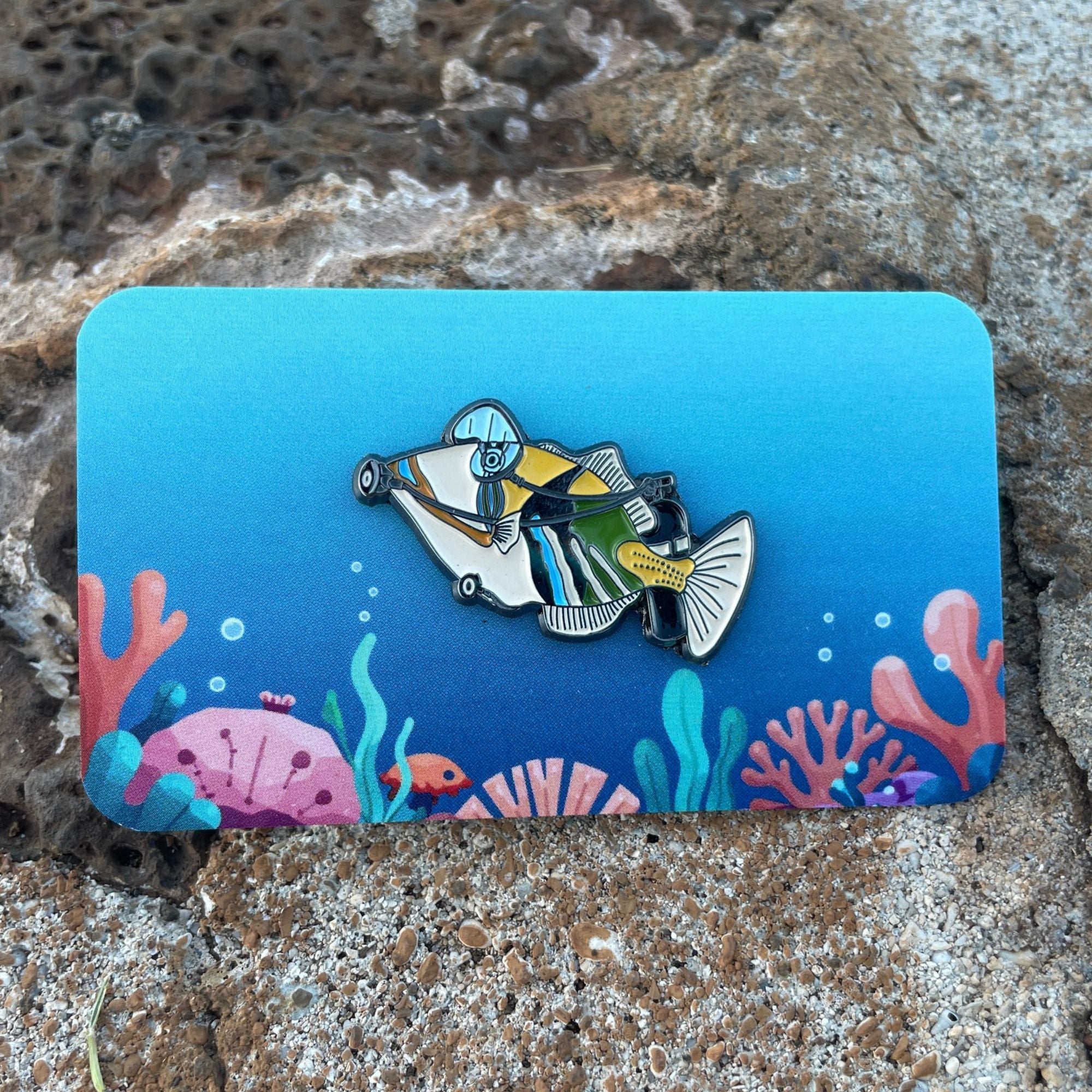 Humuhumunukunukuāpuaʻa Scuba Diver Enamel Pin 🐠🤿 on a colorful ocean themed backing card. Made by Golden Toad Studios, sold by Rinn Stitches