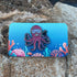 Purple octopus enamel pin on ocean themed backing card. Made by Golden Toad Studios, sold by Rinn Stitches