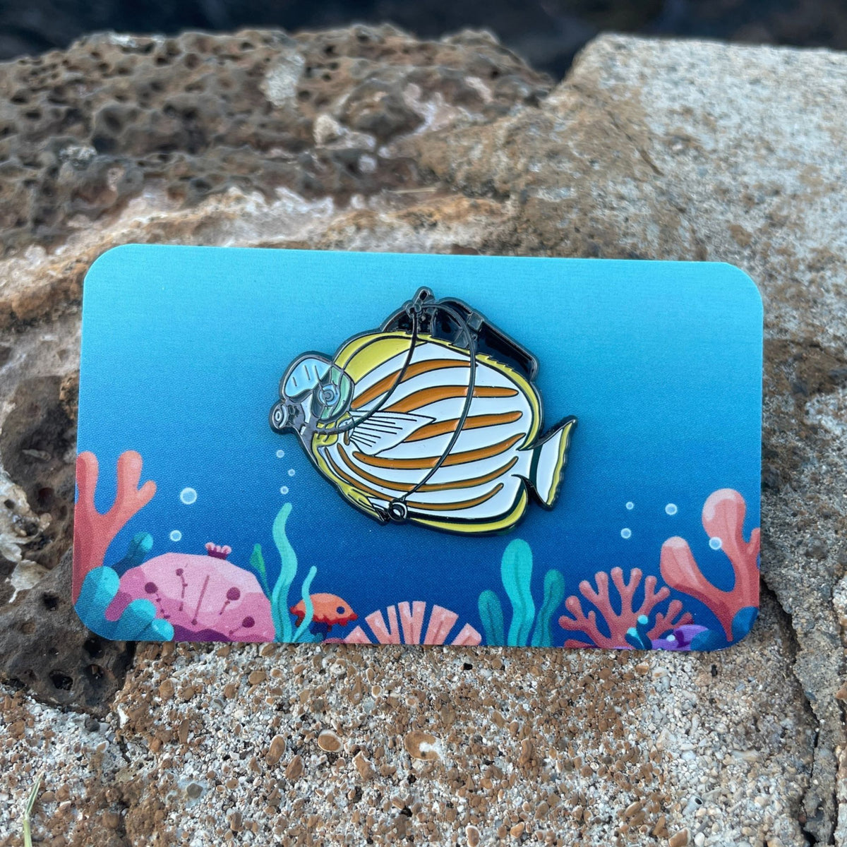 Ornate Butterfly Fish enamel pin on a colorful ocean theme backer card. Made by Golden Toad Studio, sold by Rinn Stitches.