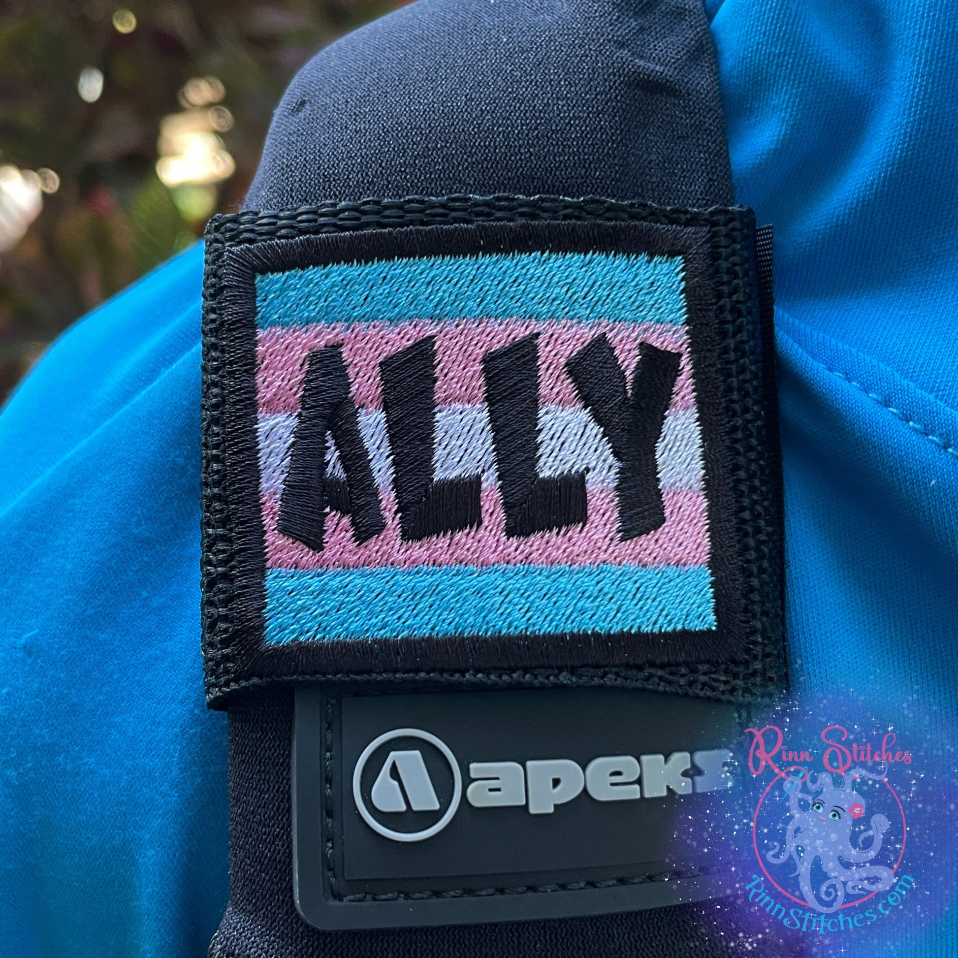 Transgender Flag Personalized BCD Tag featuring the name Ally in Black Thread. Made in the 2x2 backplate and wing size by Rinn Stitches in Maui, Hawaii
